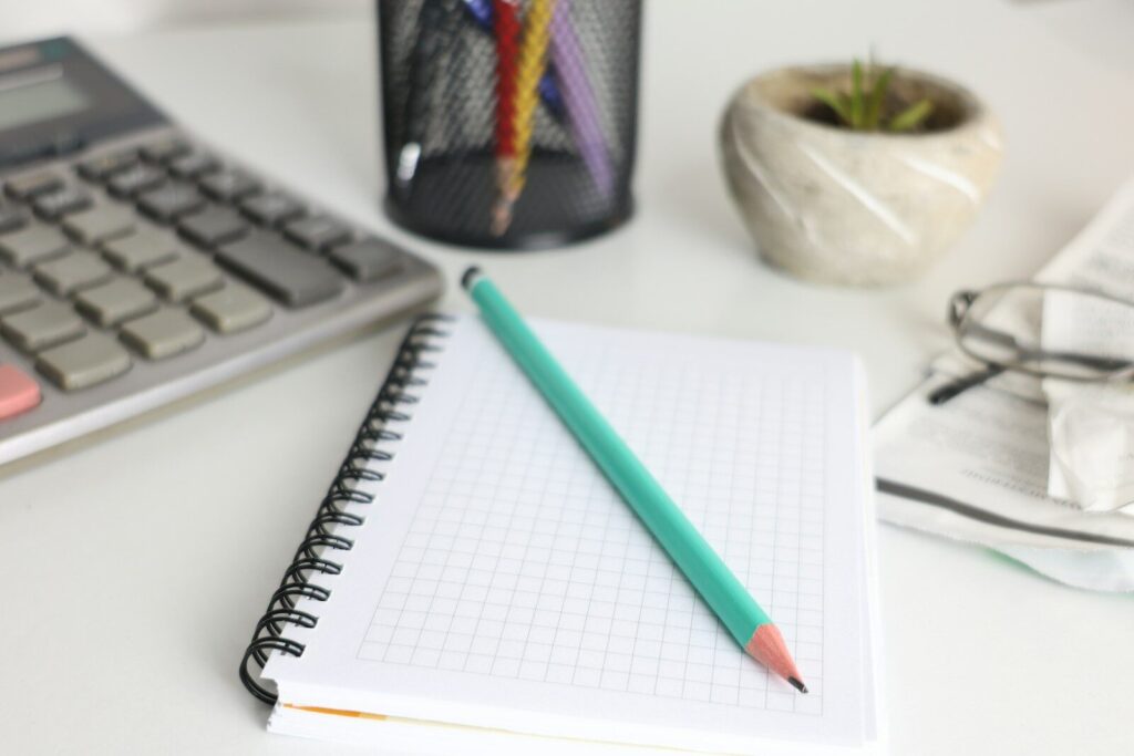 Desk with calculator, notebook, pencil, and plant