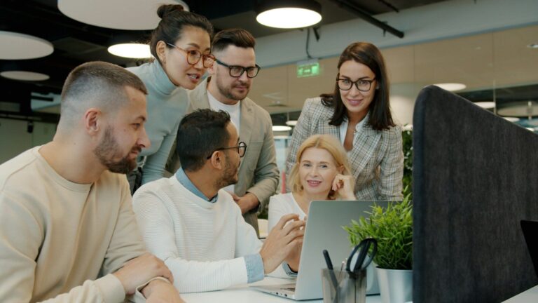 Diverse team collaborating around a laptop in office